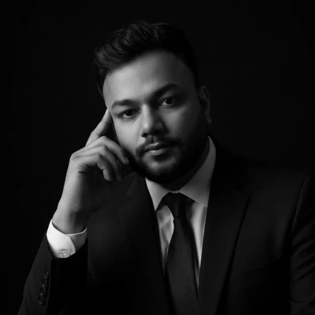 Black-and-white portrait of Shameem Ahmmed in a dark suit, resting his hand thoughtfully near his temple